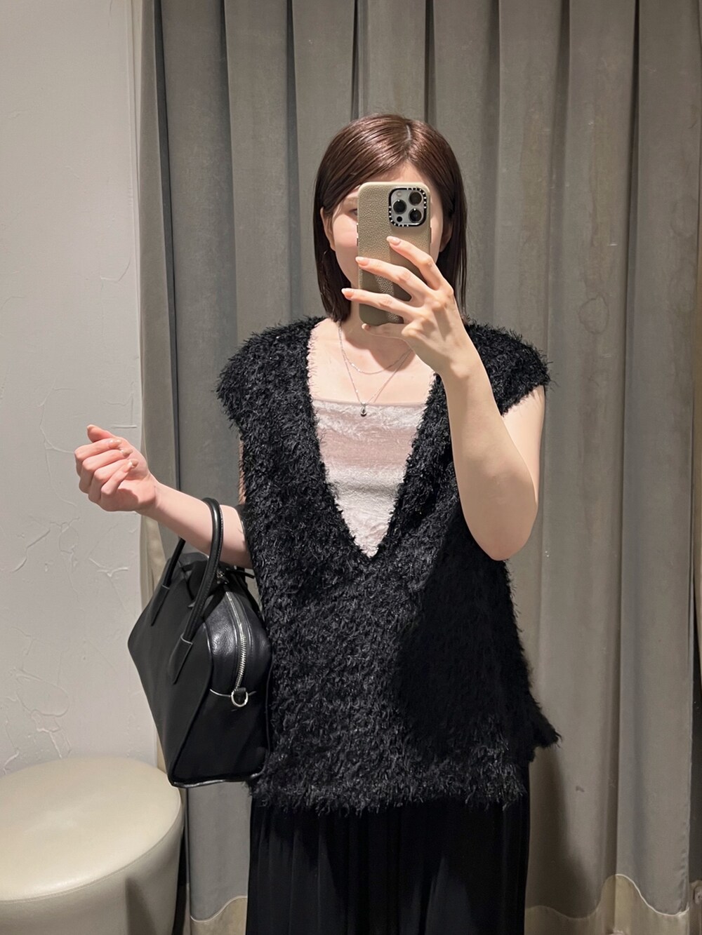 ブラック系のベスト、ブラック系のスカート、ブラック系のボストンバッグを着用したレディースの夏コーディネートの3枚目の写真