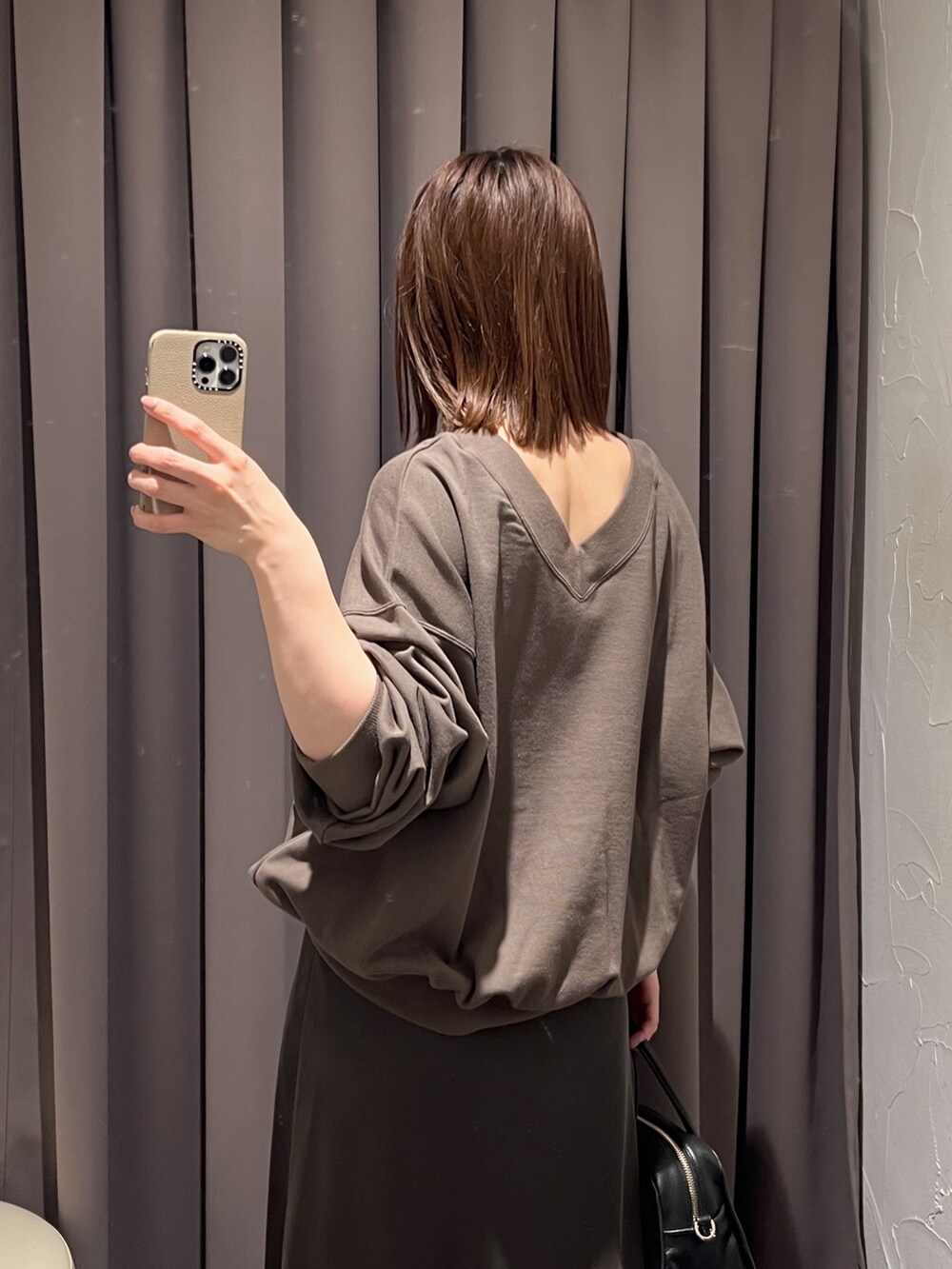 ブラウン系のスカート、ブラック系のボストンバッグ、ブラック系のパンプスを着用したレディースの冬コーディネートの6枚目の写真