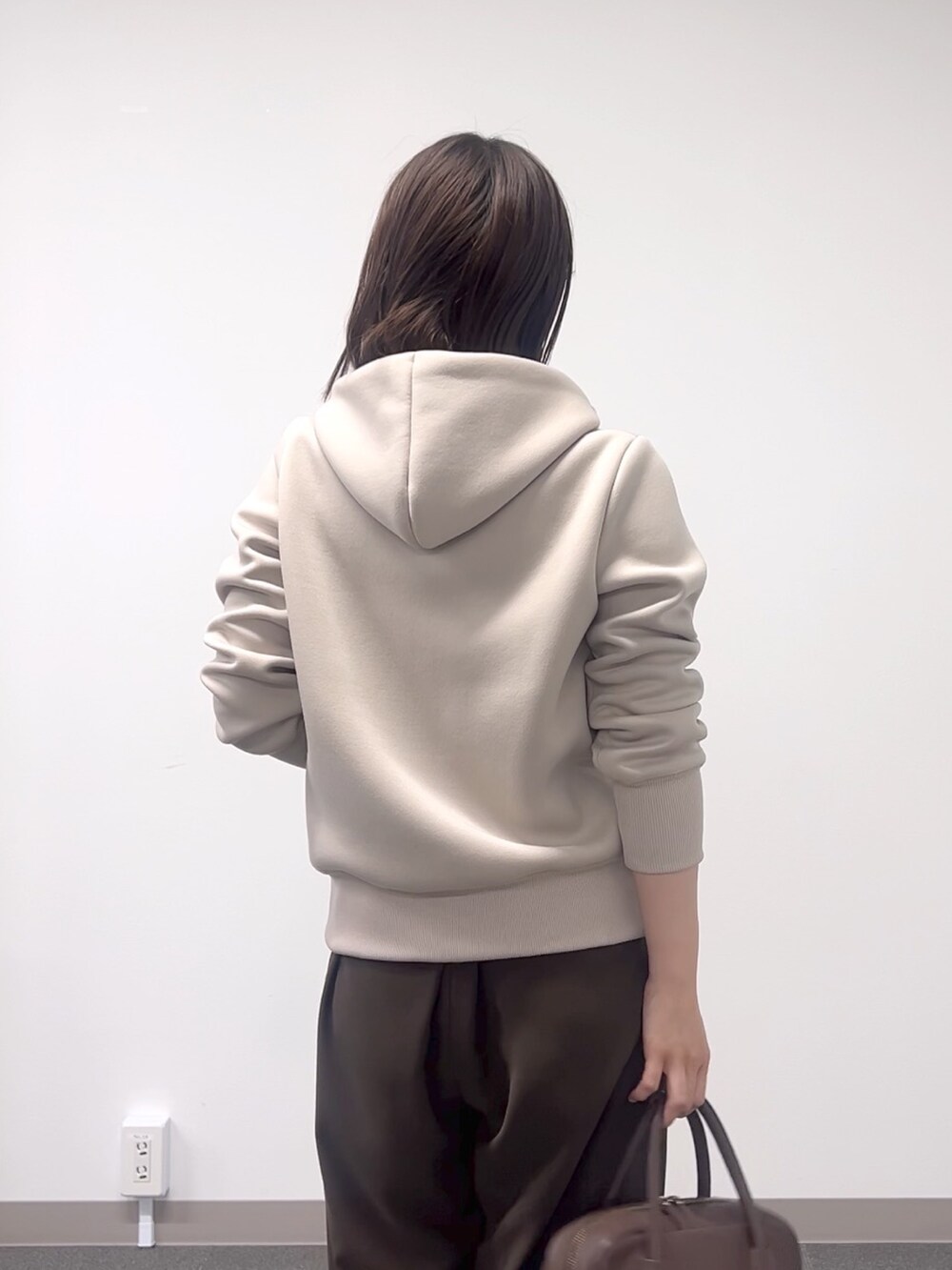 ベージュ系のパーカー、ブラウン系のスラックス、ブラウン系のボストンバッグを着用したレディースの秋コーディネートの7枚目の写真