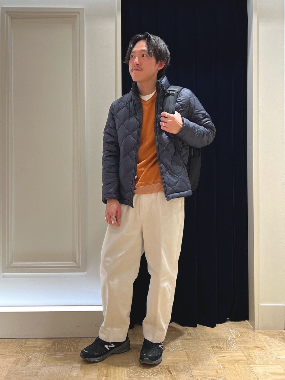 ブルー系のダウンジャケット/コート、イエロー系のニット/セーター、ブラック系のバックパック/リュックを着用したメンズの冬コーディネートの3枚目の写真