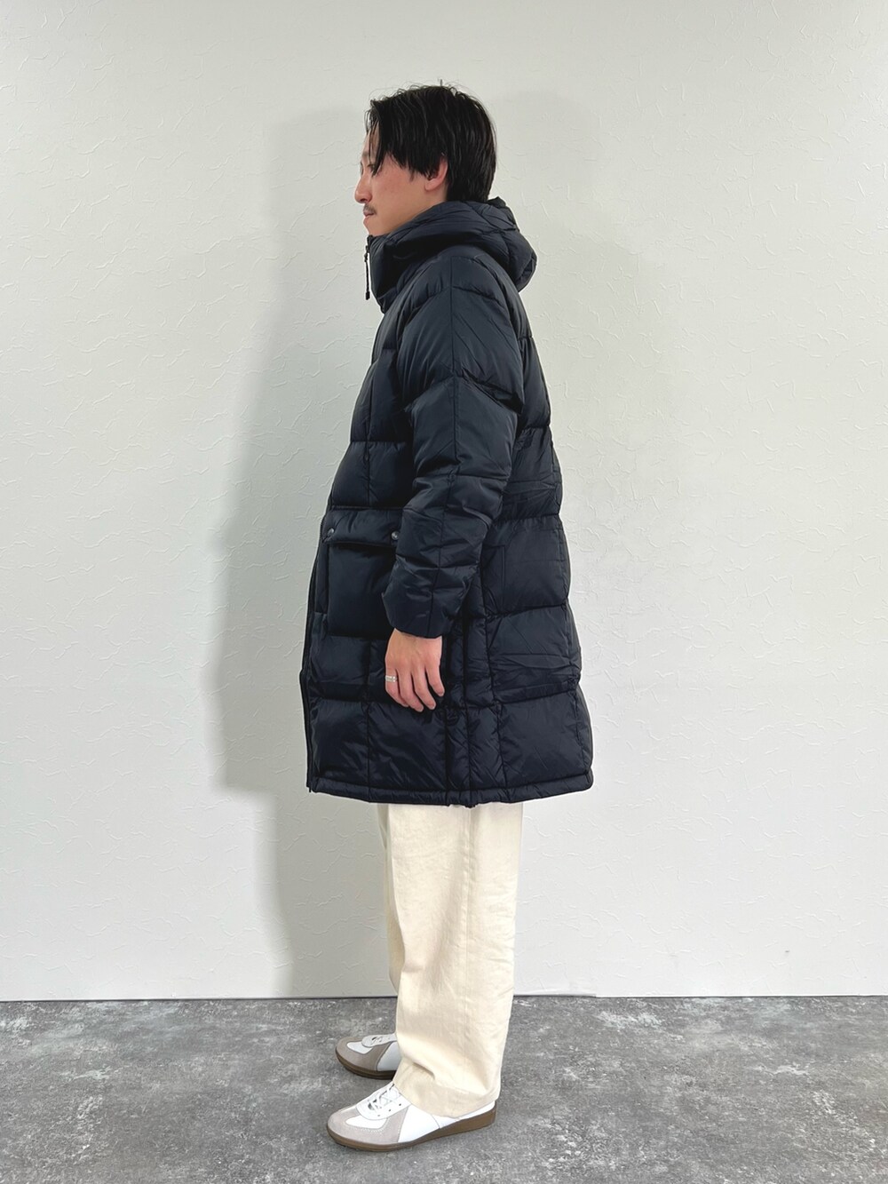 ブラック系のダウンジャケット/コート、ホワイト系のカーディガン/ボレロ、ホワイト系のTシャツ/カットソーを着用したメンズの冬コーディネートの6枚目の写真