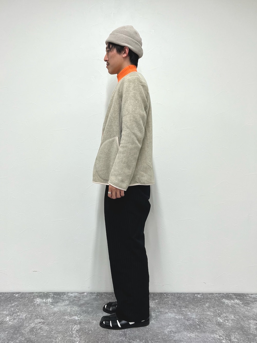 ホワイト系のブルゾン、オレンジ系のニット/セーター、ブラック系のサンダルを着用したメンズの秋コーディネートの4枚目の写真