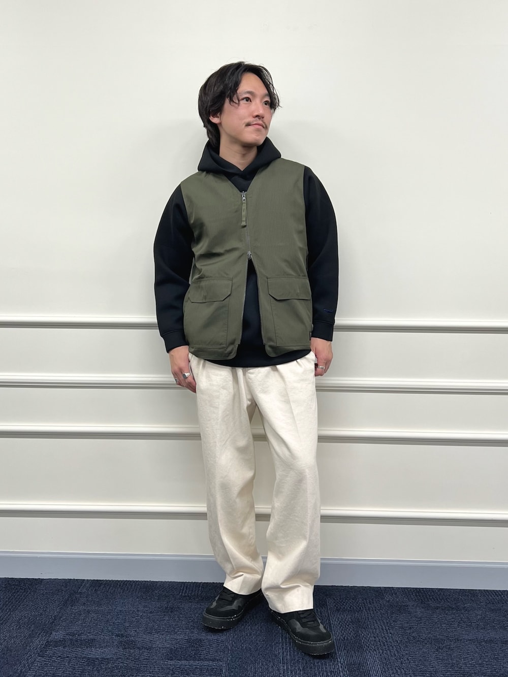 グリーン系のベスト、ブラック系のパーカー、ホワイト系のデニムパンツを着用したメンズの冬コーディネートの6枚目の写真