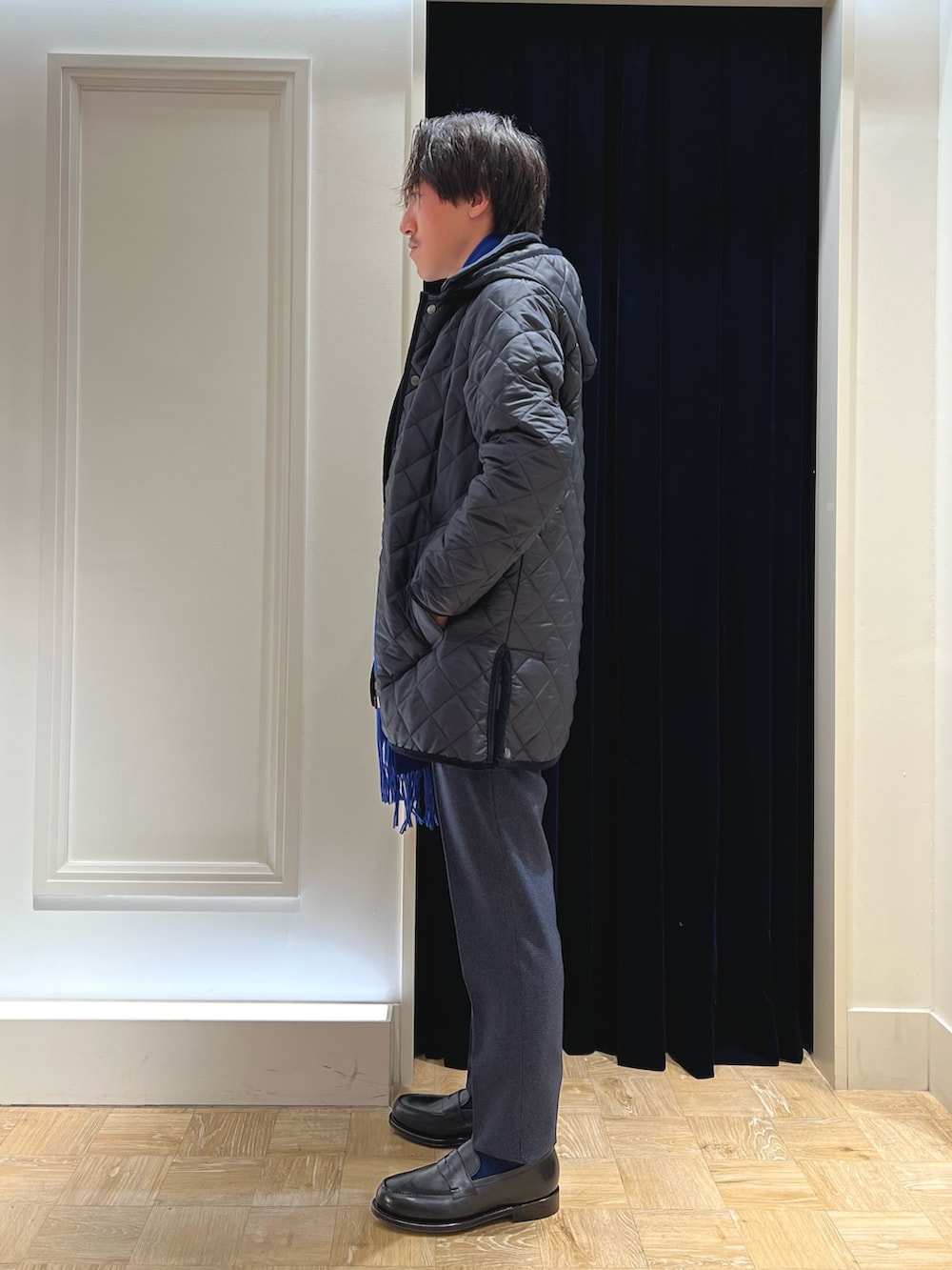 ブルー系のスラックス、ブラック系のローファー、ブルー系のネクタイを着用したメンズの冬コーディネートの4枚目の写真