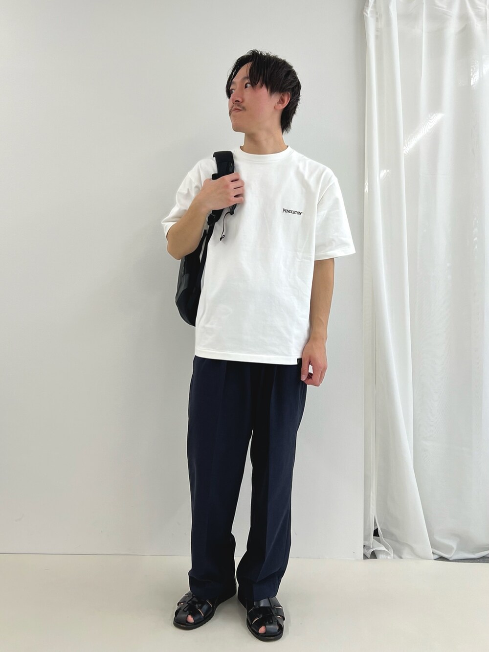 ホワイト系のTシャツ/カットソー、グレー系のバックパック/リュック、ブラック系のその他パンツを着用したメンズの春コーディネートの2枚目の写真