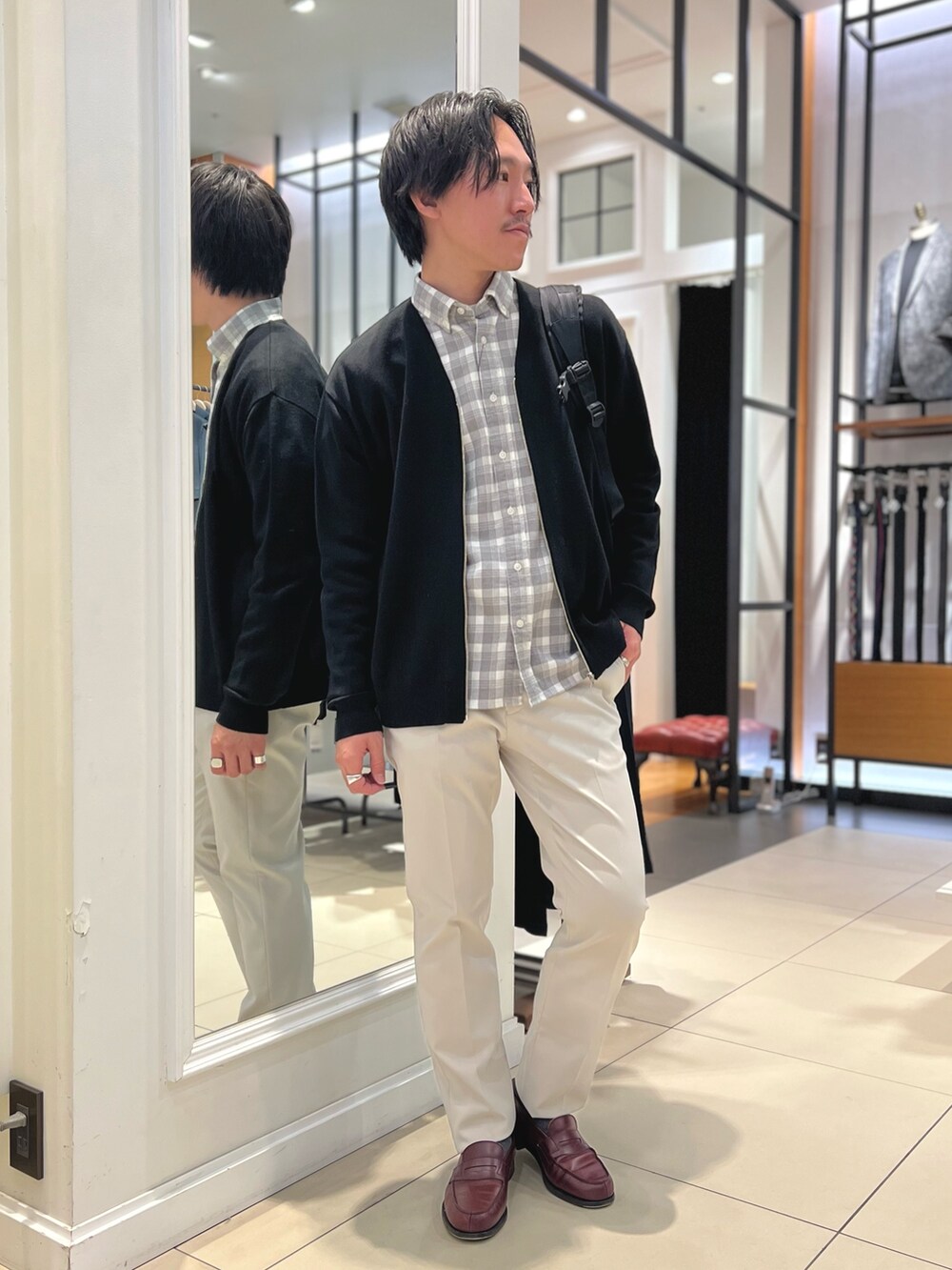 ブラック系のカーディガン/ボレロ、ブラック系のバックパック/リュック、ホワイト系のチノパンツを着用したメンズの冬コーディネートの4枚目の写真