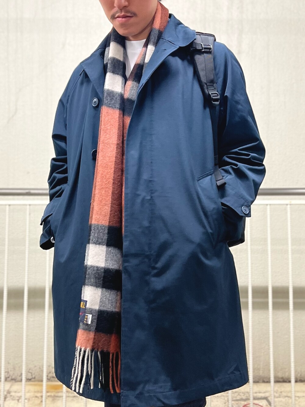 ブラック系のバックパック/リュック、ホワイト系のTシャツ/カットソー、ブルー系のステンカラーコートを着用したメンズの秋コーディネートの7枚目の写真