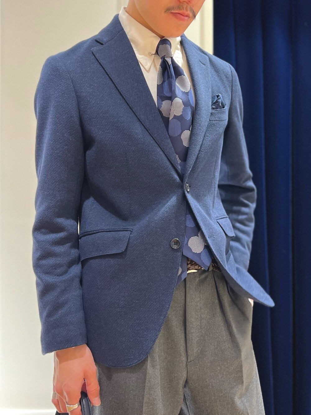 ブルー系のテーラードジャケット、ブルー系のネクタイ、ブルー系のトートバッグを着用したメンズの冬コーディネートの6枚目の写真