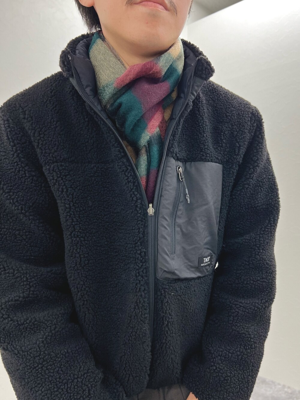 ブラック系のブルゾン、ベージュ系のニット/セーター、グレー系のマフラーを着用したメンズの秋コーディネートの7枚目の写真