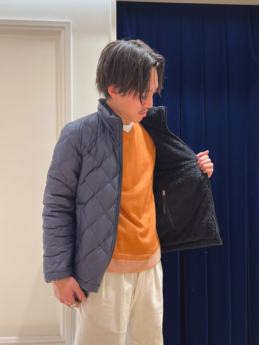 ブルー系のダウンジャケット/コート、イエロー系のニット/セーター、ブラック系のバックパック/リュックを着用したメンズの冬コーディネートの6枚目の写真