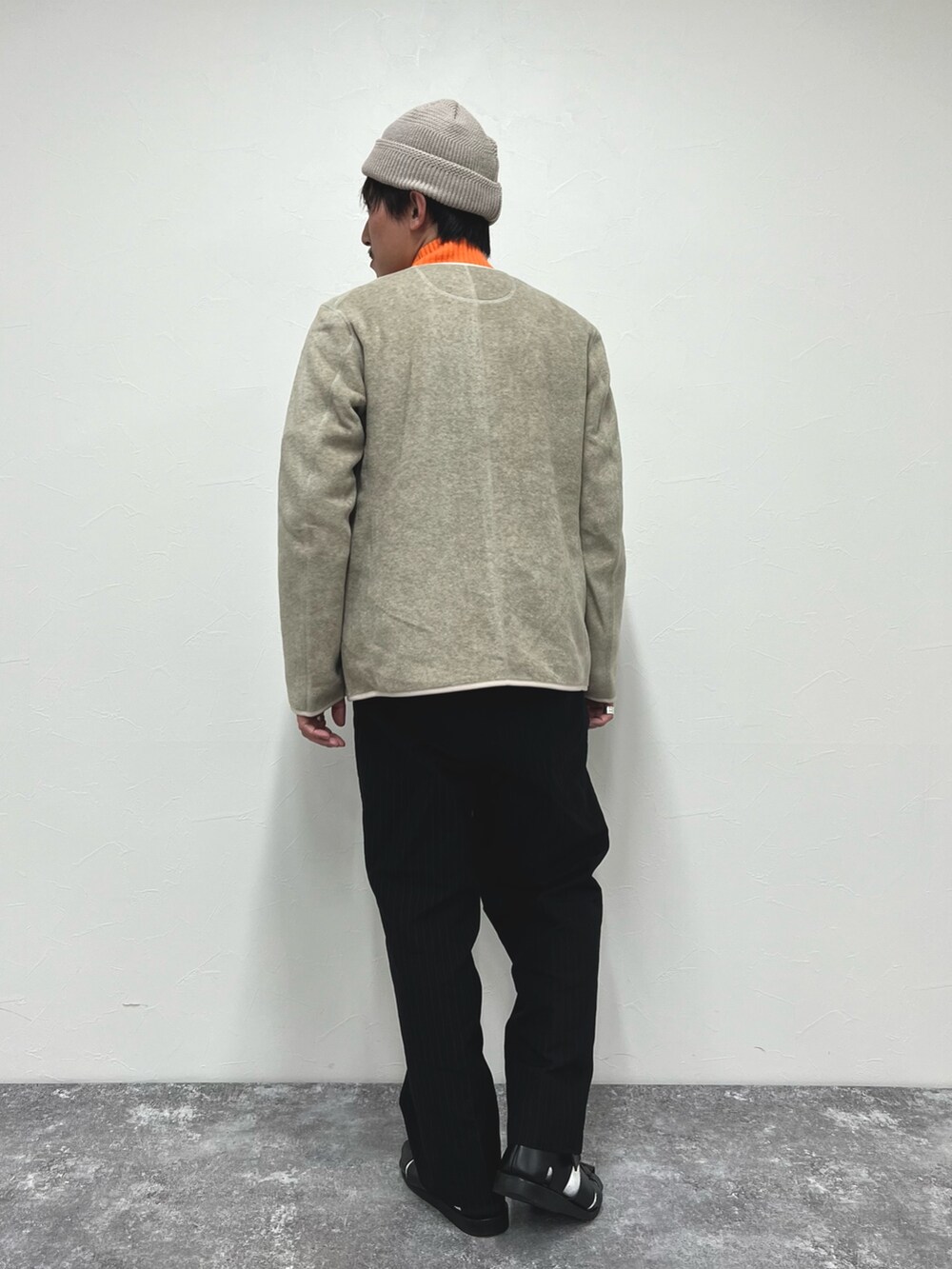 ホワイト系のブルゾン、オレンジ系のニット/セーター、ブラック系のサンダルを着用したメンズの秋コーディネートの5枚目の写真