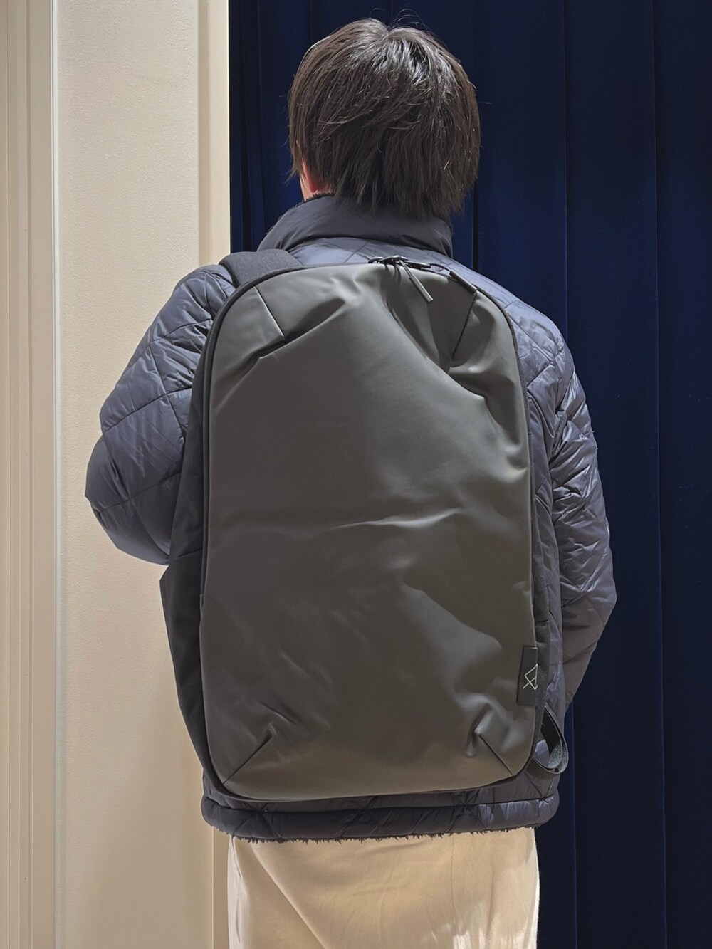 ブルー系のダウンジャケット/コート、イエロー系のニット/セーター、ブラック系のバックパック/リュックを着用したメンズの冬コーディネートの7枚目の写真