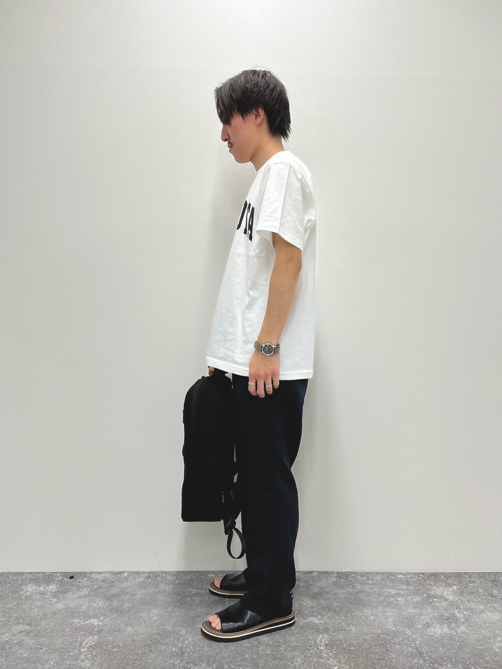 ホワイト系のTシャツ/カットソー、ブラック系のバックパック/リュック、ブラック系のサンダルを着用したメンズの春コーディネートの4枚目の写真