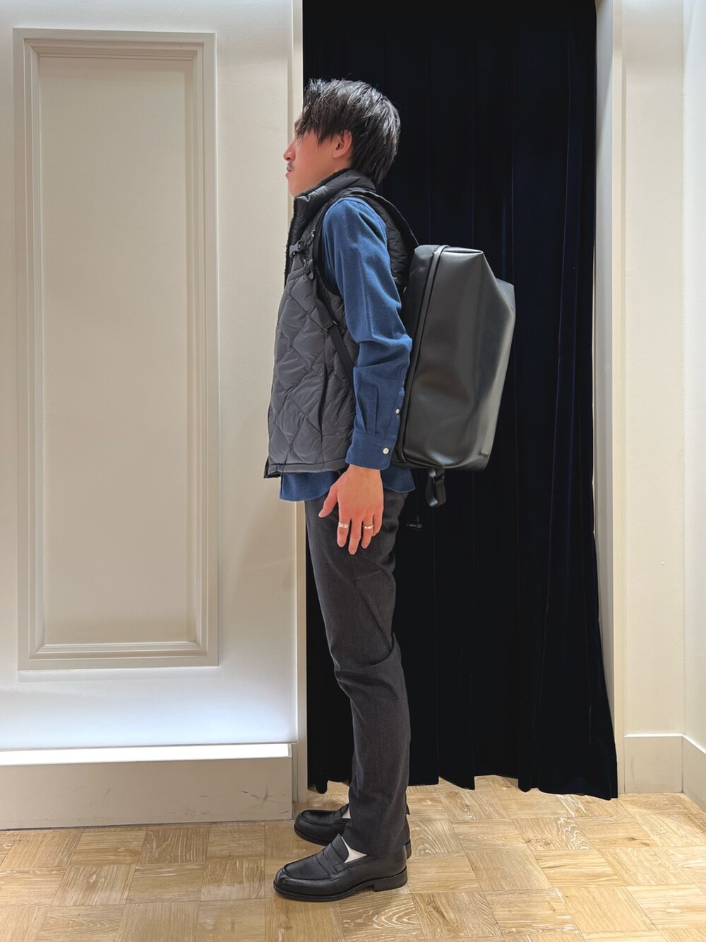 グレー系のダウンベスト、ブルー系のシャツ/ブラウス、ブラック系のバックパック/リュックを着用したメンズの冬コーディネートの4枚目の写真