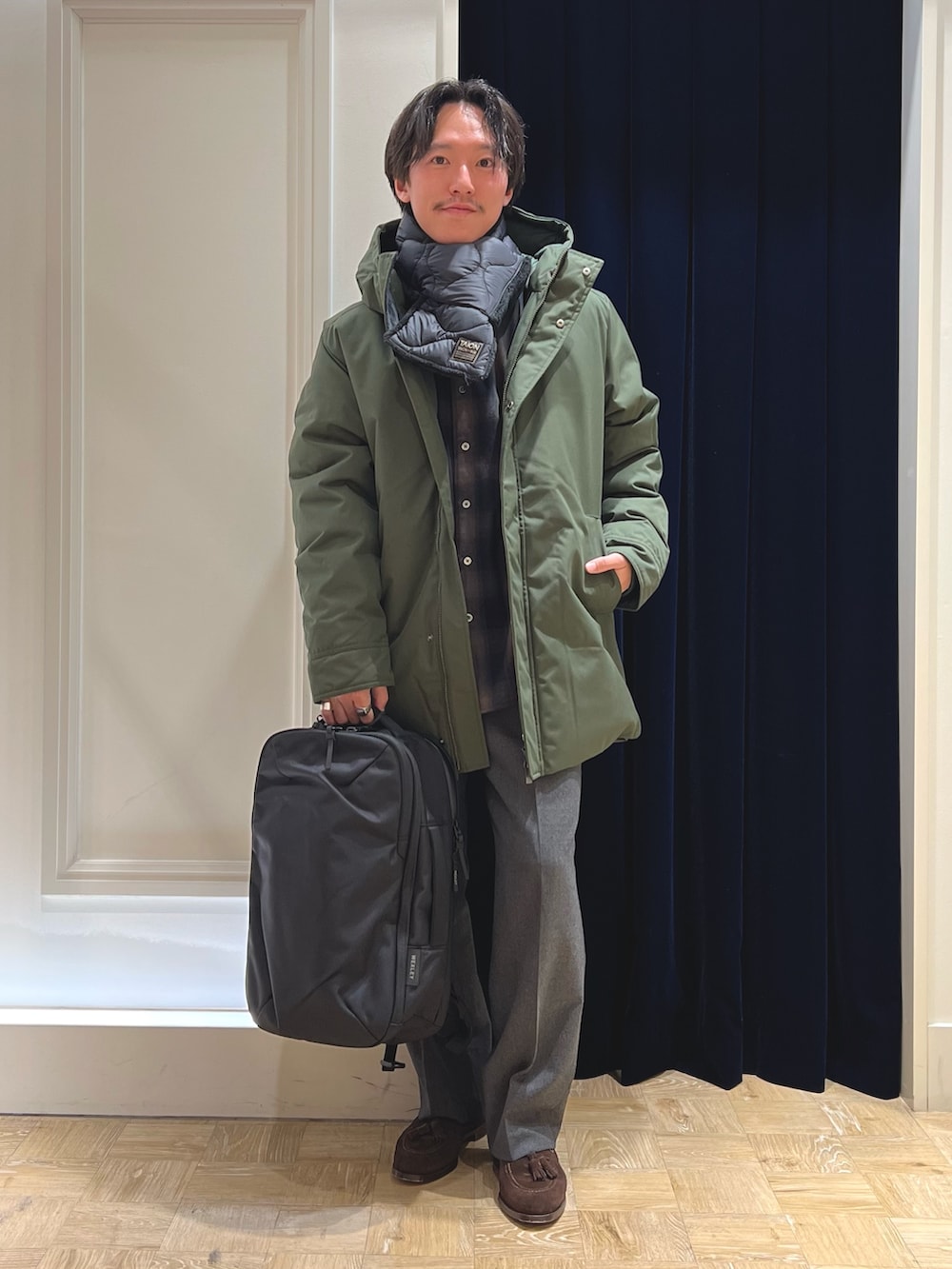 グリーン系のシャツ/ブラウス、ブラック系のバックパック/リュック、グリーン系のダウンジャケット/コートを着用したメンズの冬コーディネートの2枚目の写真
