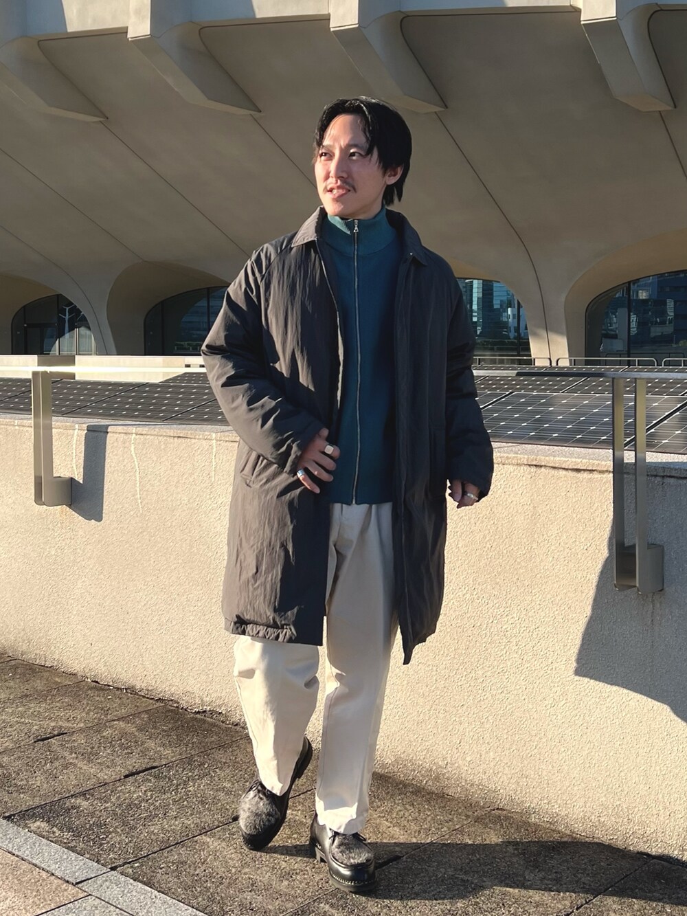 グレー系のダウンジャケット/コート、ブルー系のニット/セーター、ブラック系のその他シューズを着用したメンズの秋コーディネートの3枚目の写真