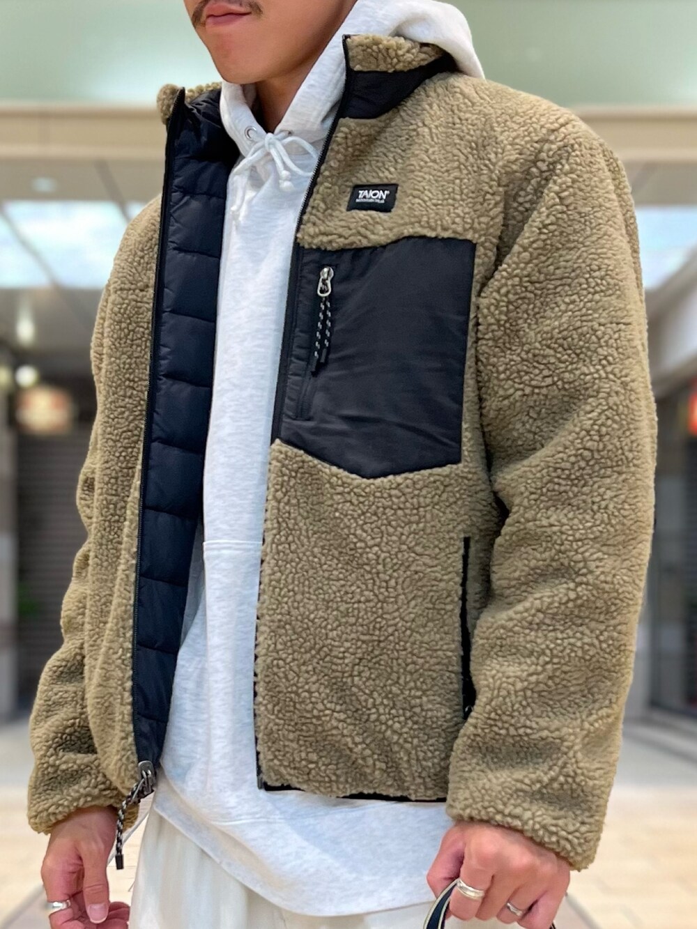 ベージュ系のダウンジャケット/コート、グレー系のパーカー、ブラック系のトートバッグを着用したメンズの秋コーディネートの6枚目の写真