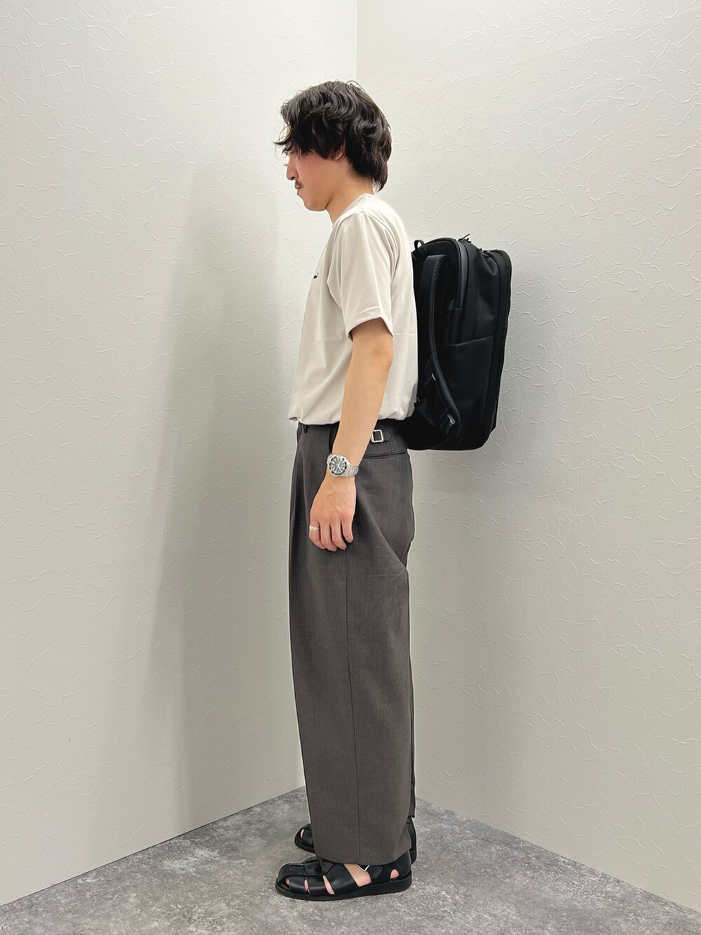 ベージュ系のTシャツ/カットソー、ブラック系のバックパック/リュック、ブラック系のサンダルを着用したメンズの春コーディネートの5枚目の写真
