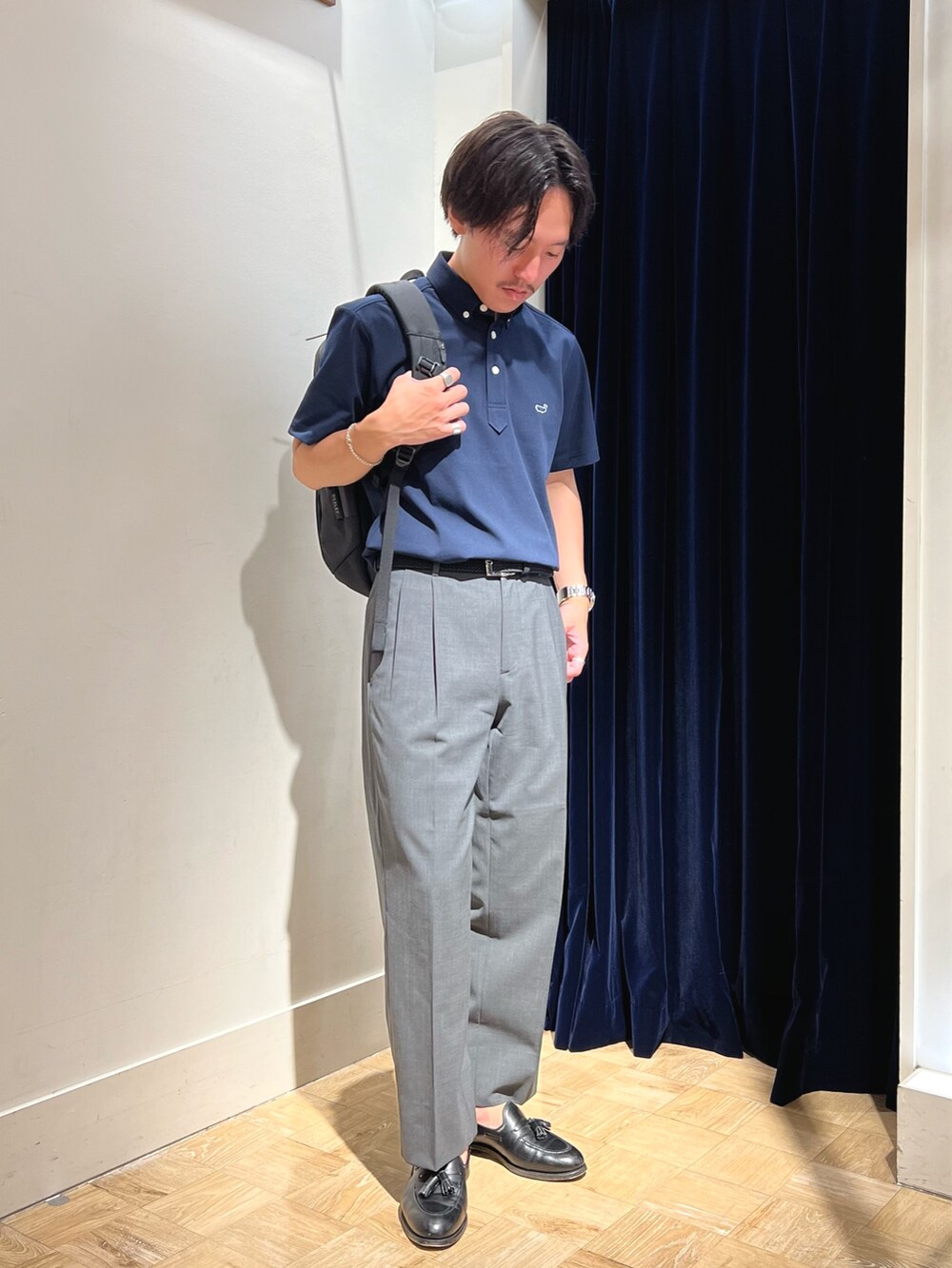 ブルー系のポロシャツ、ブラック系のバックパック/リュック、ブラック系のベルトを着用したメンズの夏コーディネートの3枚目の写真