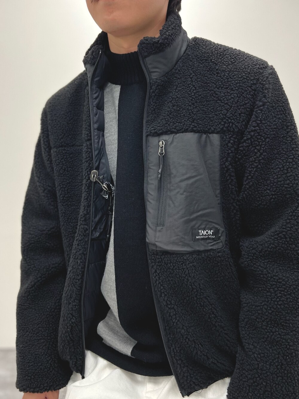 ブラック系のニット/セーター、ホワイト系のデニムパンツ、ブラック系のブルゾンを着用したメンズの冬コーディネートの6枚目の写真