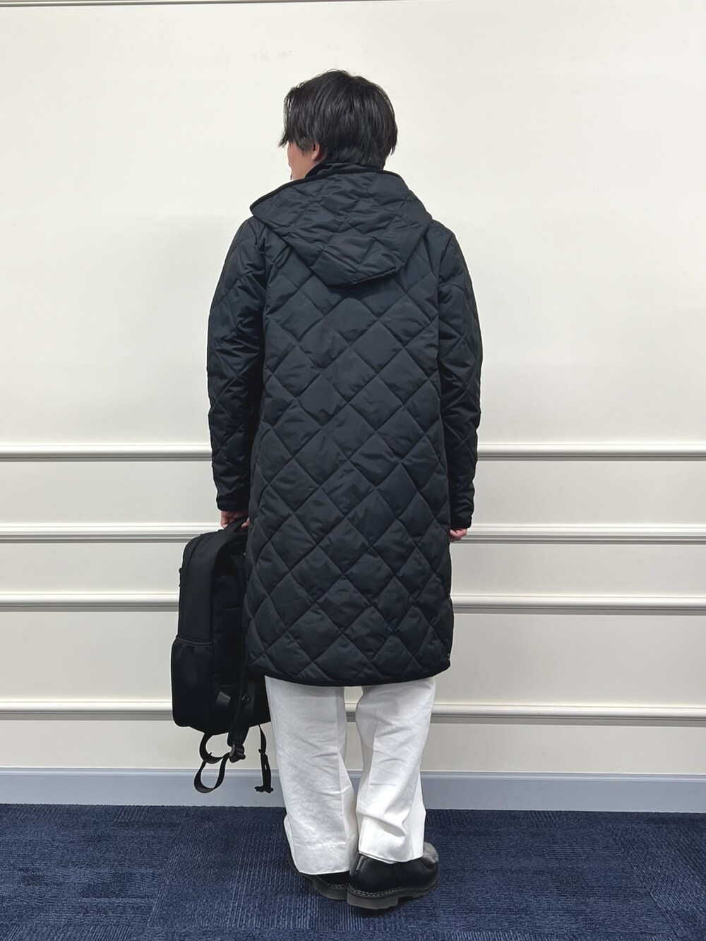 ブラック系のダウンジャケット/コート、ブラック系のバックパック/リュック、ベージュ系のカーディガン/ボレロを着用したメンズの冬コーディネートの8枚目の写真