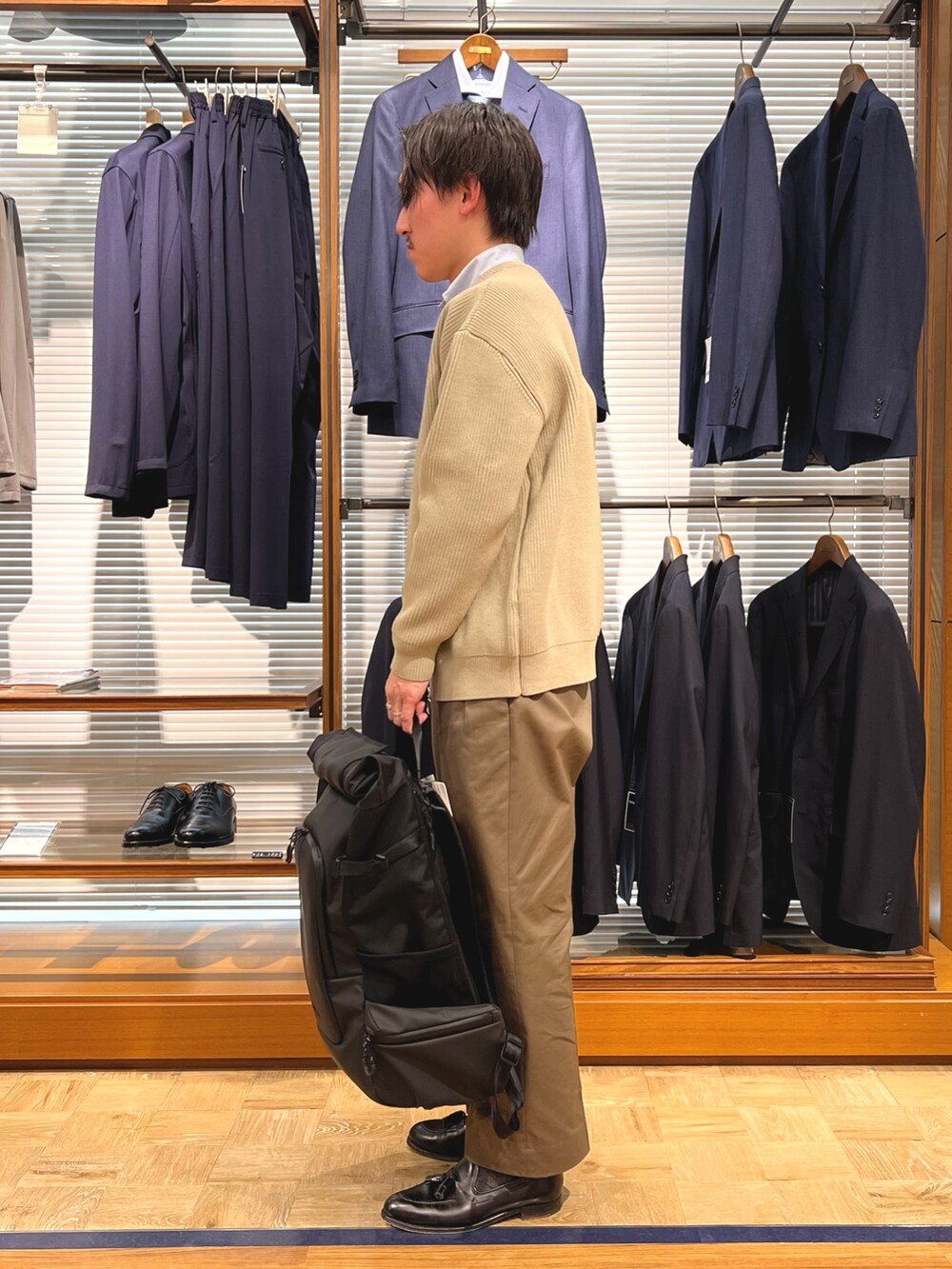 ベージュ系のカーディガン/ボレロ、ブラック系のバックパック/リュック、ブラック系のローファーを着用したメンズの春コーディネートの4枚目の写真