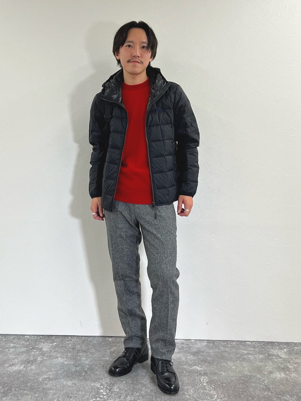 ブラック系のダウンジャケット/コート、レッド系のニット/セーター、グレー系のスラックスを着用したメンズの秋コーディネートの3枚目の写真