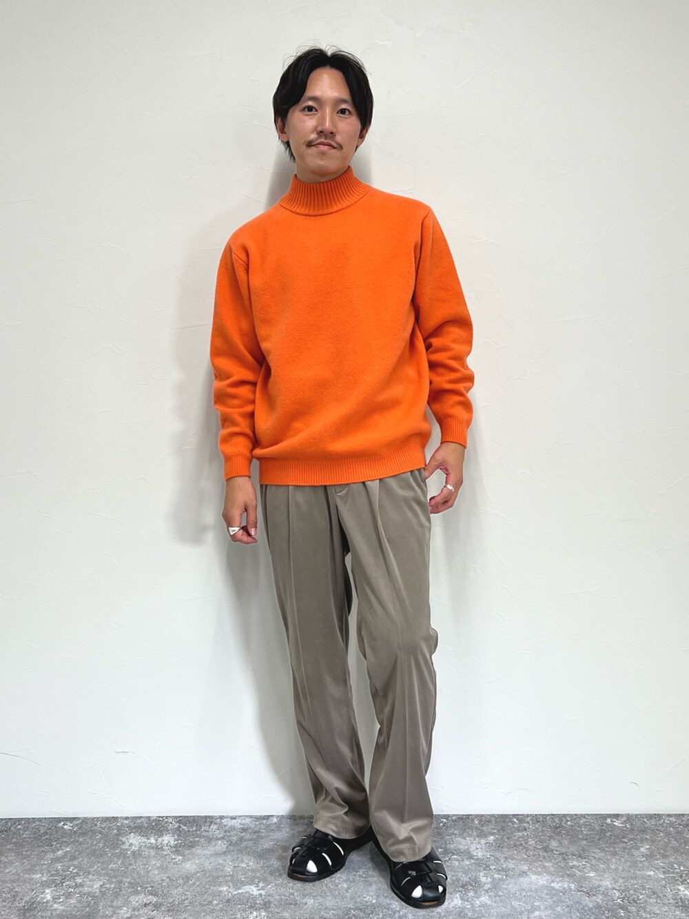 オレンジ系のニット/セーター、ブラック系のミリタリージャケット、ベージュ系のその他パンツを着用したメンズの秋コーディネートの5枚目の写真