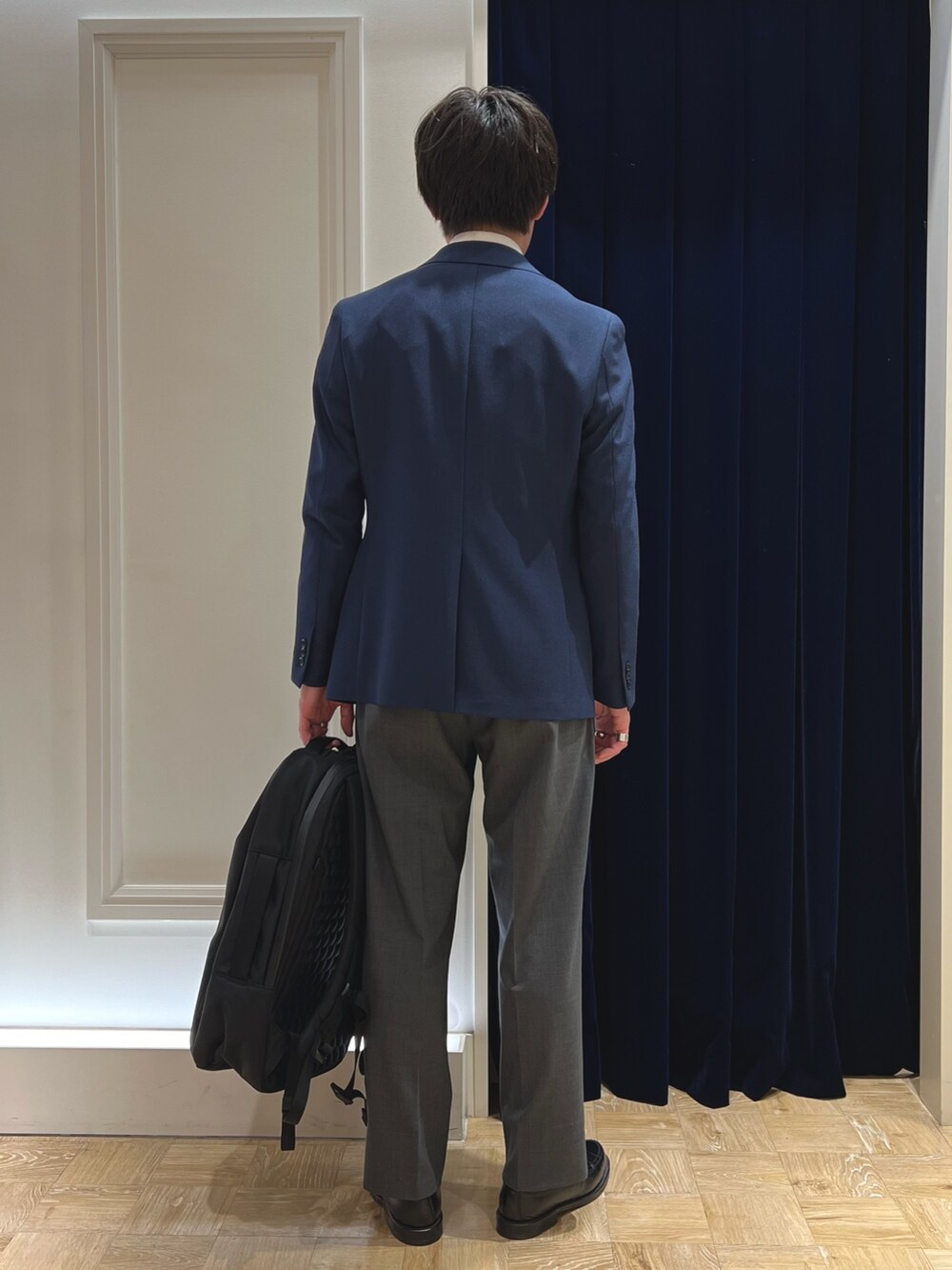 ブルー系のネクタイ、ブルー系のテーラードジャケット、ブラック系のバックパック/リュックを着用したメンズの春コーディネートの6枚目の写真
