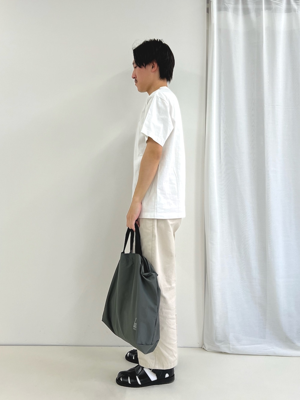 ホワイト系のTシャツ/カットソー、グレー系のトートバッグ、ブラック系のサンダルを着用したメンズの春コーディネートの4枚目の写真
