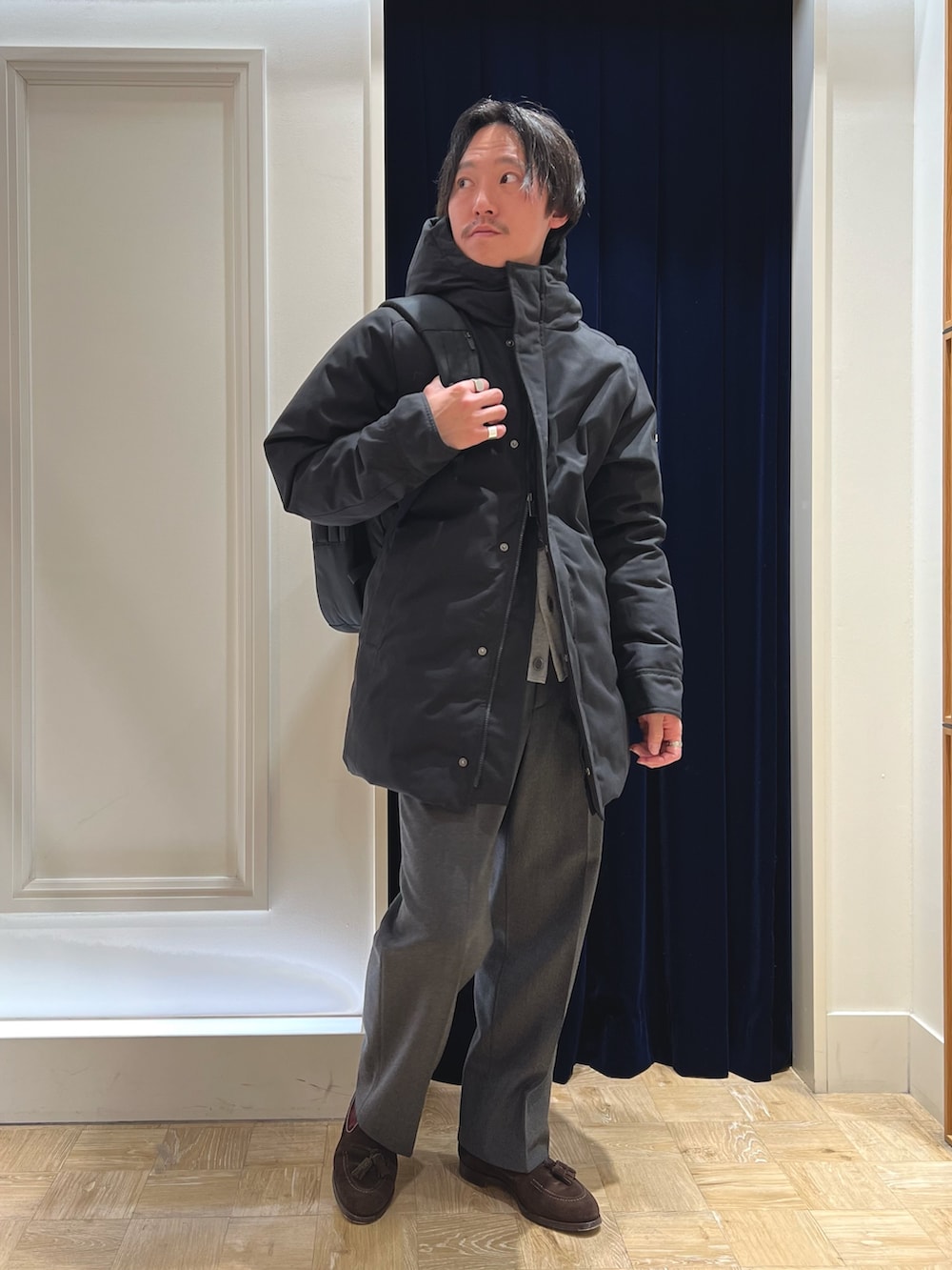 ブラック系のダウンジャケット/コート、グレー系のカーディガン/ボレロ、ブラック系のバックパック/リュックを着用したメンズの冬コーディネートの3枚目の写真