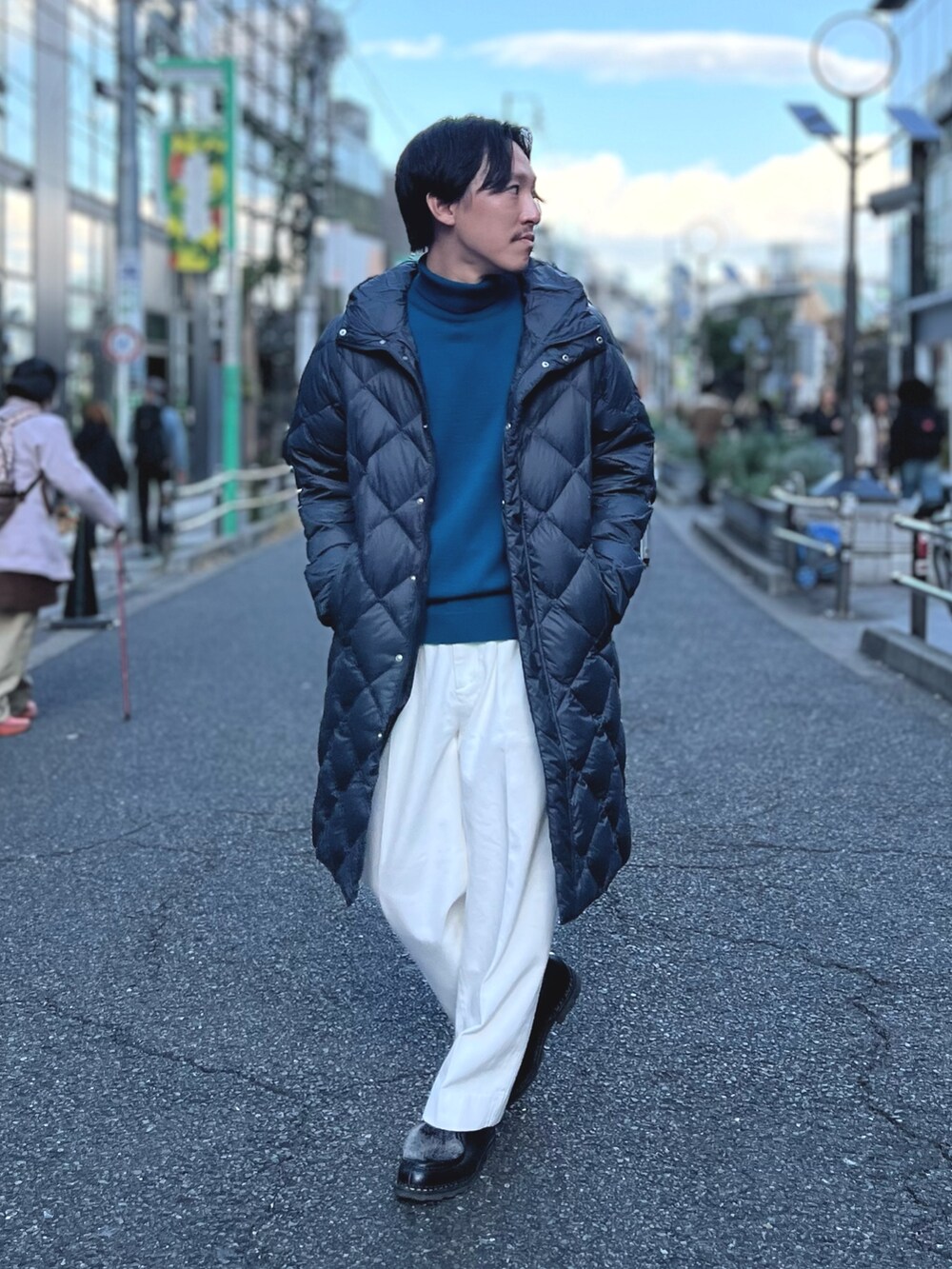 グレー系のダウンジャケット/コート、ブルー系のニット/セーター、ホワイト系のデニムパンツを着用したメンズの冬コーディネートの4枚目の写真