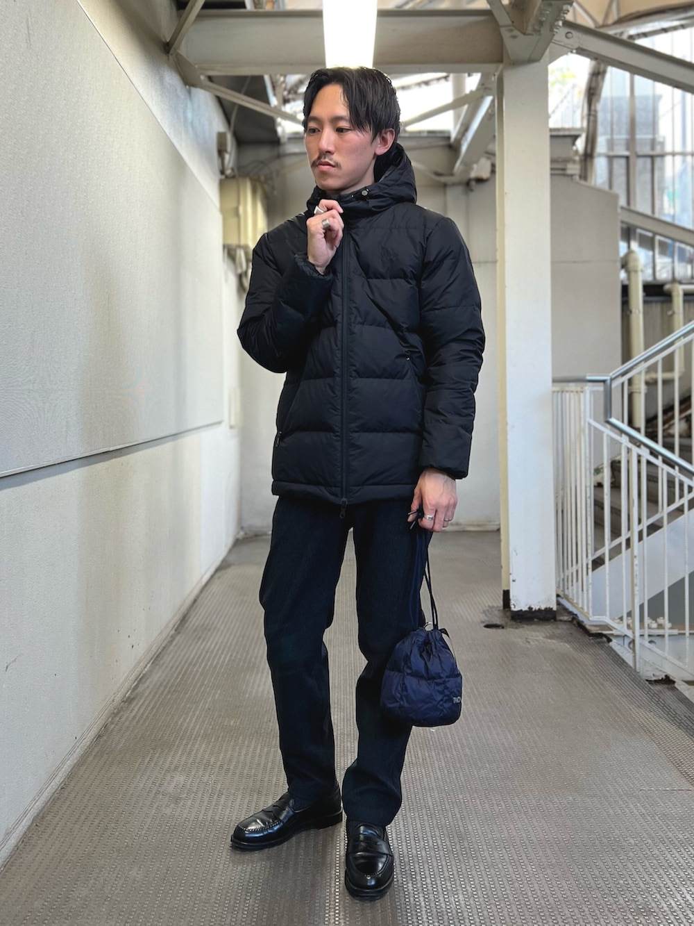 ブラック系のダウンジャケット/コート、ブルー系のショルダーバッグ、ブルー系のその他パンツを着用したメンズの冬コーディネートの2枚目の写真