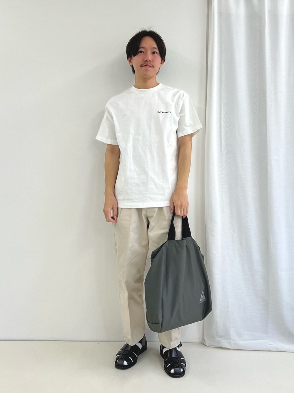 ホワイト系のTシャツ/カットソー、グレー系のトートバッグ、ブラック系のサンダルを着用したメンズの春コーディネートの3枚目の写真