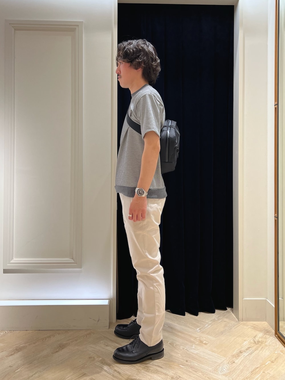 グレー系のTシャツ/カットソー、ブラック系のショルダーバッグ、ホワイト系のチノパンツを着用したメンズの春コーディネートの4枚目の写真