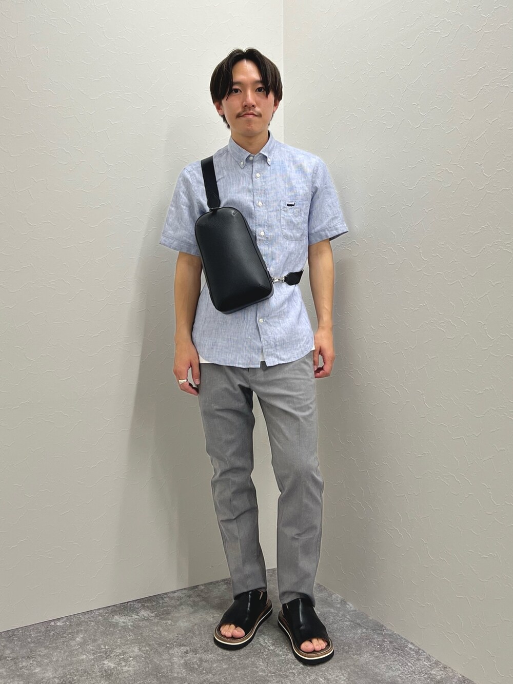 ブルー系のシャツ/ブラウス、ブラック系のボディバッグ/ウエストポーチ、グレー系のチノパンツを着用したメンズの春コーディネートの2枚目の写真