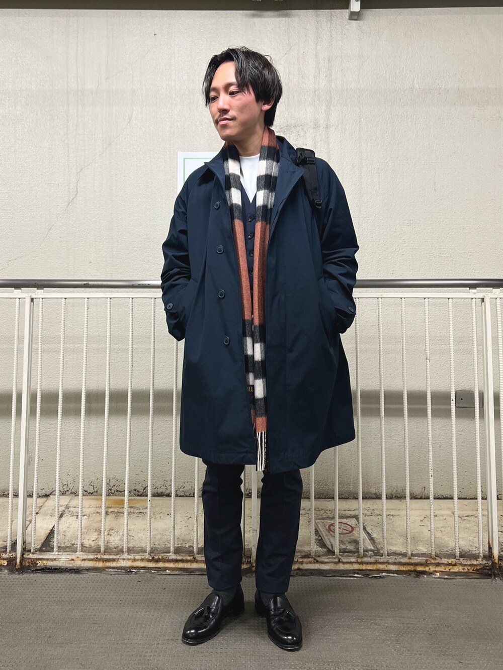 ブラック系のバックパック/リュック、ホワイト系のTシャツ/カットソー、ブルー系のステンカラーコートを着用したメンズの秋コーディネートの4枚目の写真