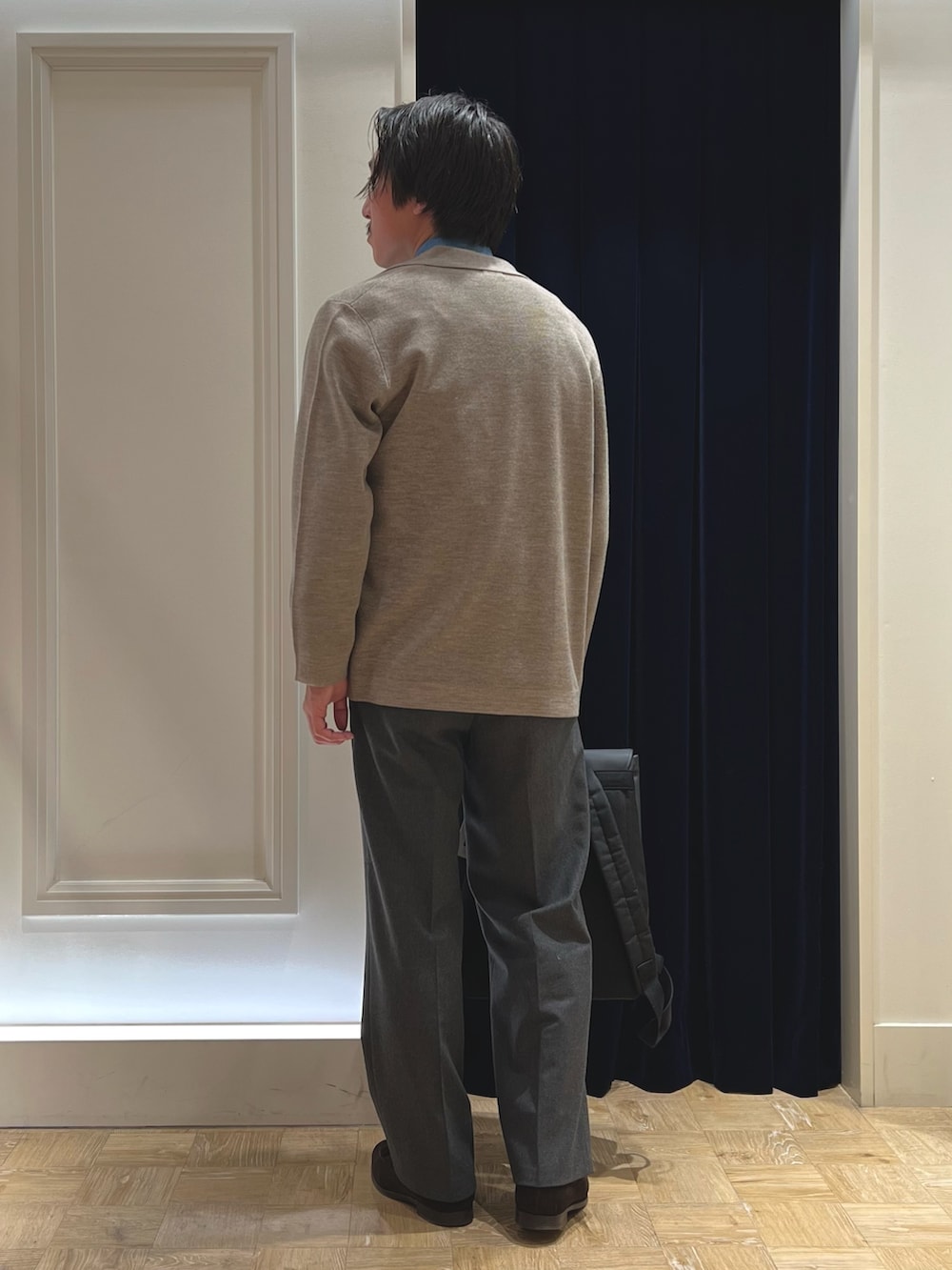 ベージュ系のテーラードジャケット、ブラック系のダウンベスト、ブラック系のバックパック/リュックを着用したメンズの冬コーディネートの8枚目の写真