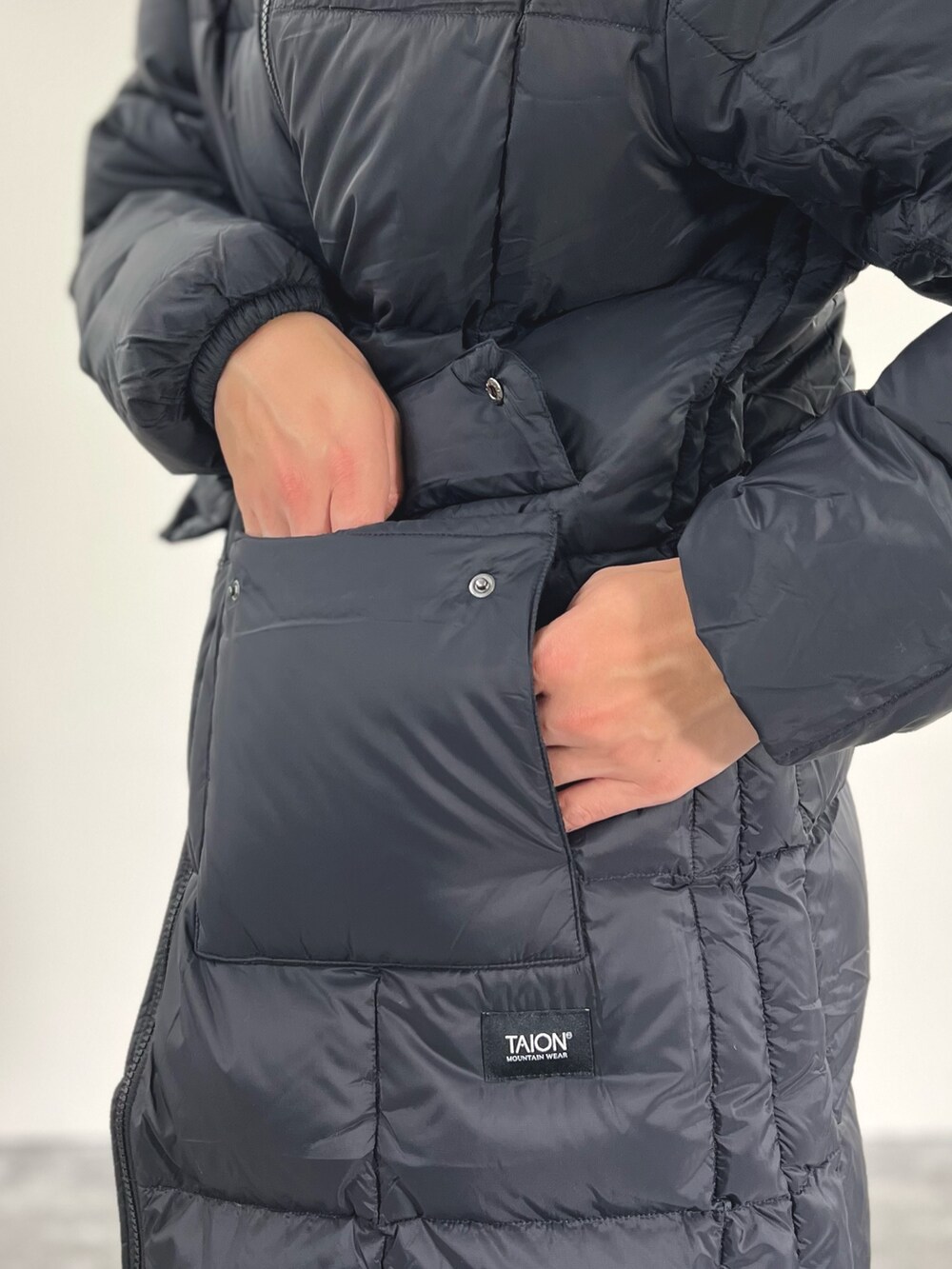 ブラック系のダウンジャケット/コート、ホワイト系のカーディガン/ボレロ、ホワイト系のTシャツ/カットソーを着用したメンズの冬コーディネートの9枚目の写真