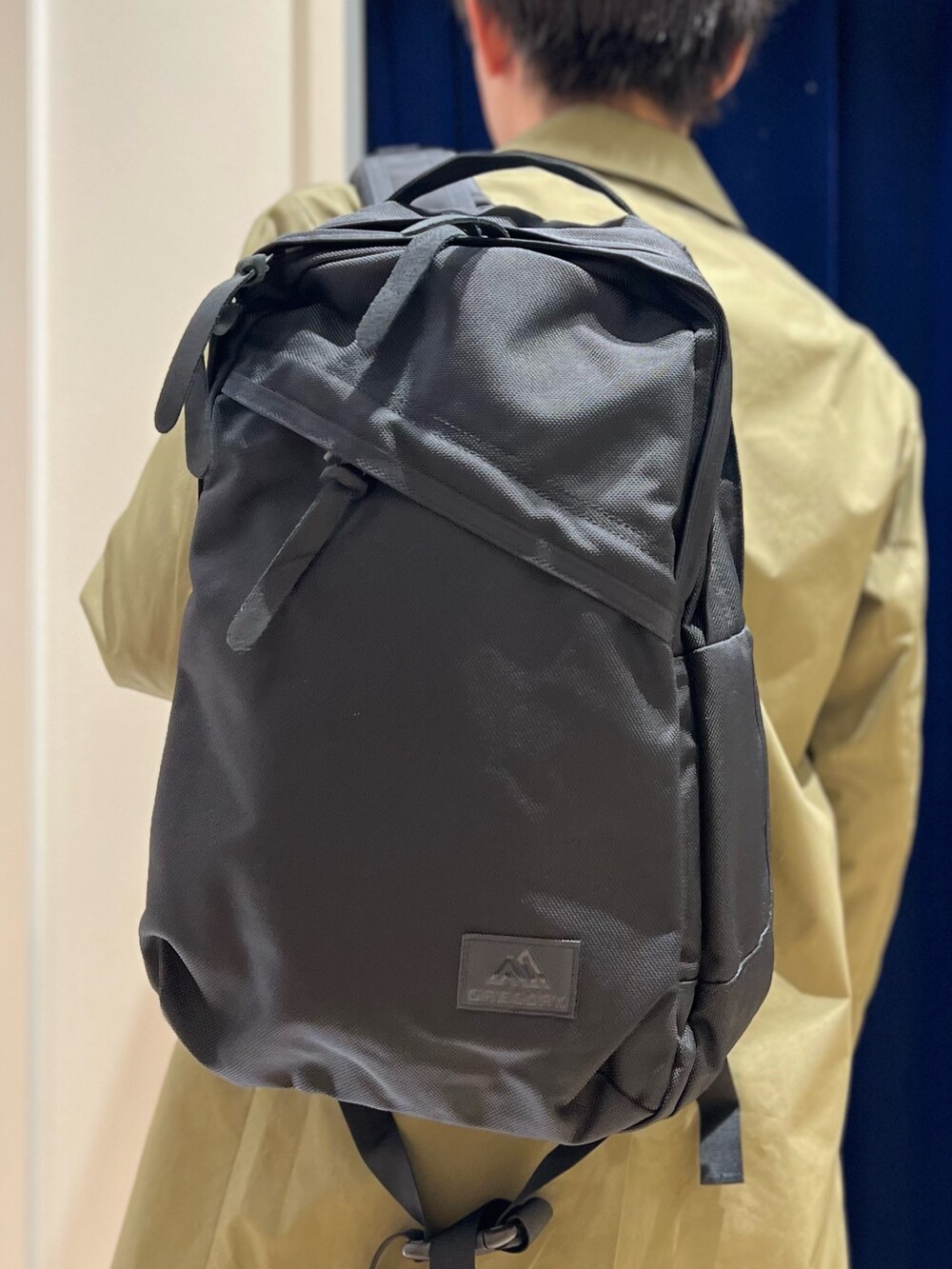 ベージュ系のシャツ/ブラウス、グリーン系のステンカラーコート、ブラック系のバックパック/リュックを着用したメンズの冬コーディネートの6枚目の写真