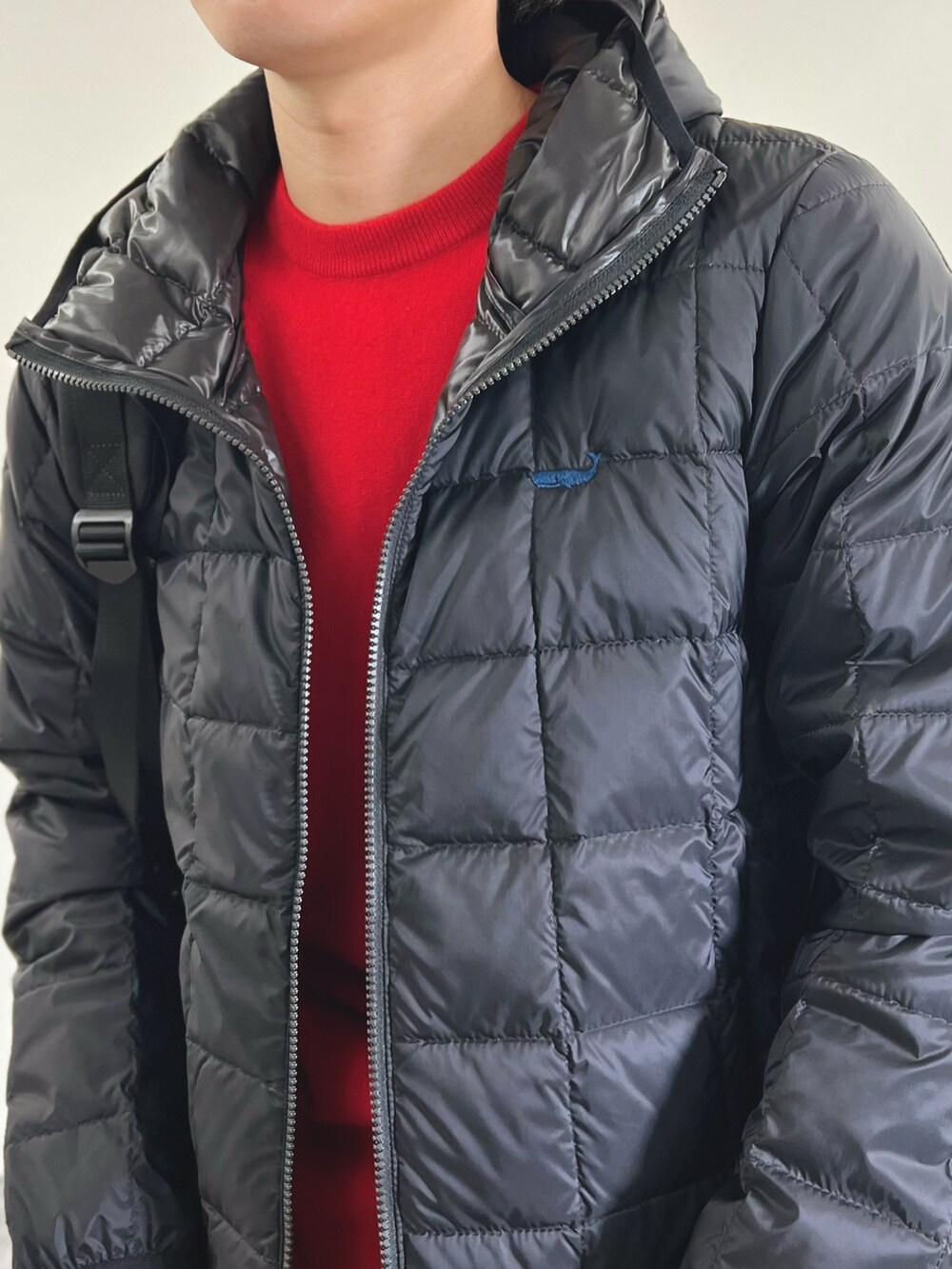 ブラック系のダウンジャケット/コート、レッド系のニット/セーター、グレー系のスラックスを着用したメンズの秋コーディネートの7枚目の写真
