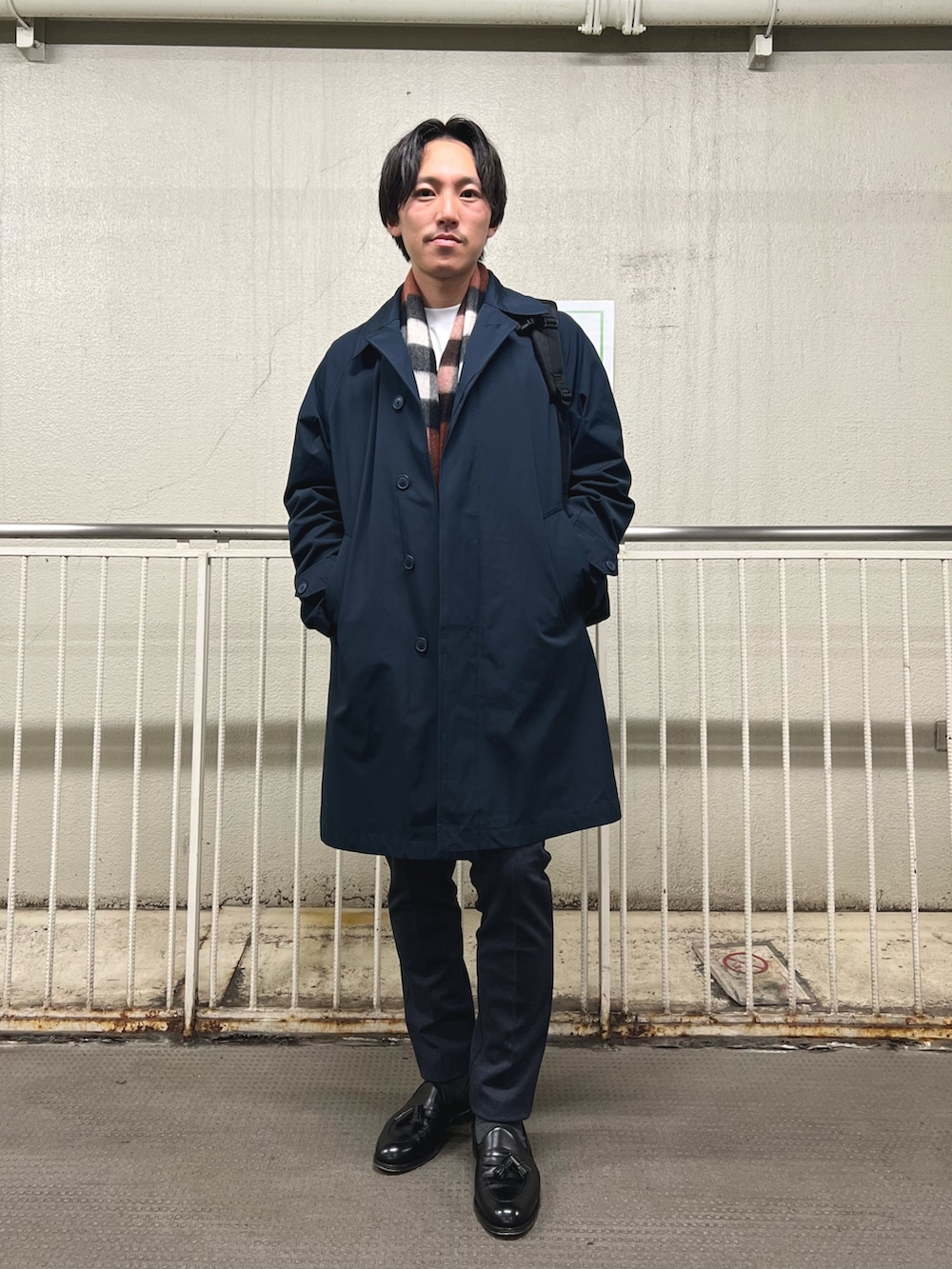 ブラック系のバックパック/リュック、ホワイト系のTシャツ/カットソー、ブルー系のステンカラーコートを着用したメンズの秋コーディネートの3枚目の写真