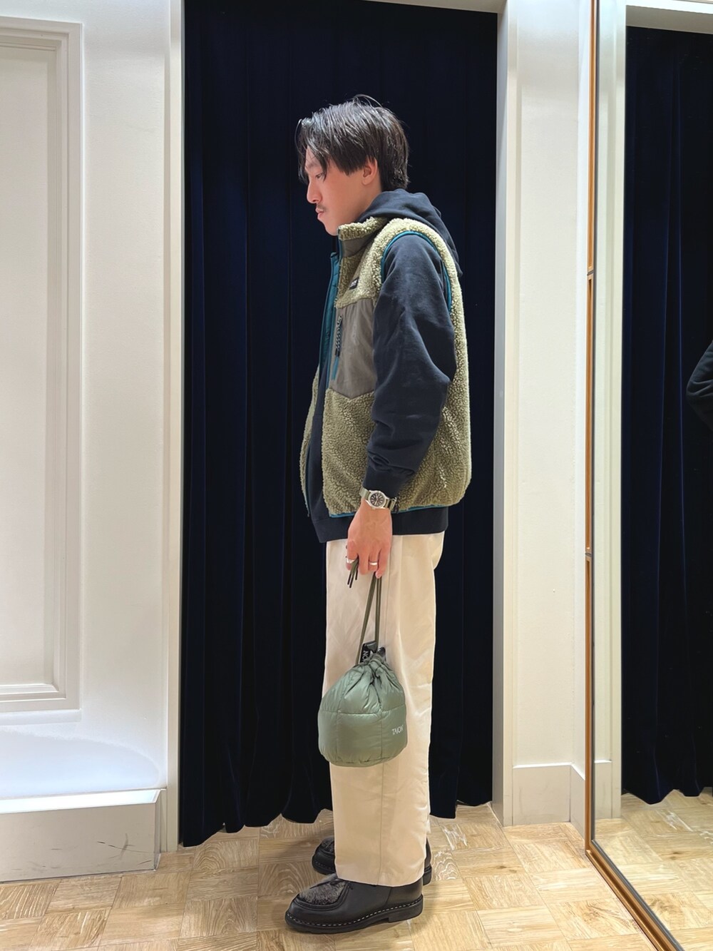 ブラック系のパーカー、グリーン系のダウンベスト、グリーン系のショルダーバッグを着用したメンズの秋コーディネートの5枚目の写真