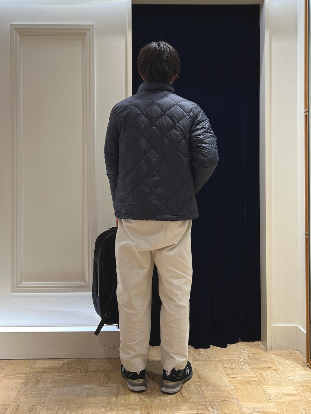 ブルー系のダウンジャケット/コート、イエロー系のニット/セーター、ブラック系のバックパック/リュックを着用したメンズの冬コーディネートの5枚目の写真