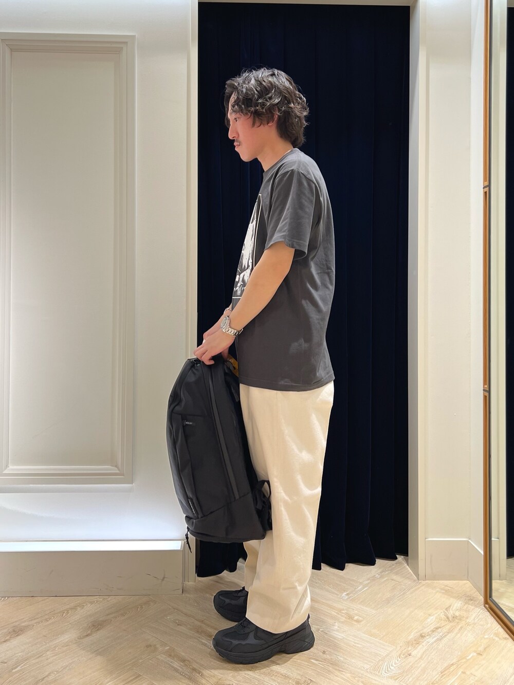 ブラック系のTシャツ/カットソー、ブラック系のバックパック/リュック、ブラック系のスニーカーを着用したメンズの春コーディネートの5枚目の写真