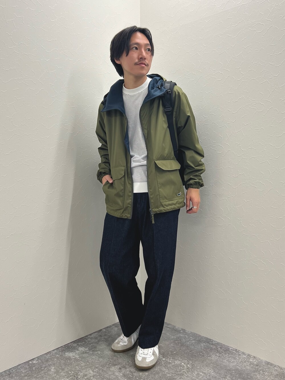 グリーン系のブルゾン、ホワイト系のTシャツ/カットソー、ブルー系のデニムパンツを着用したメンズの冬コーディネートの4枚目の写真