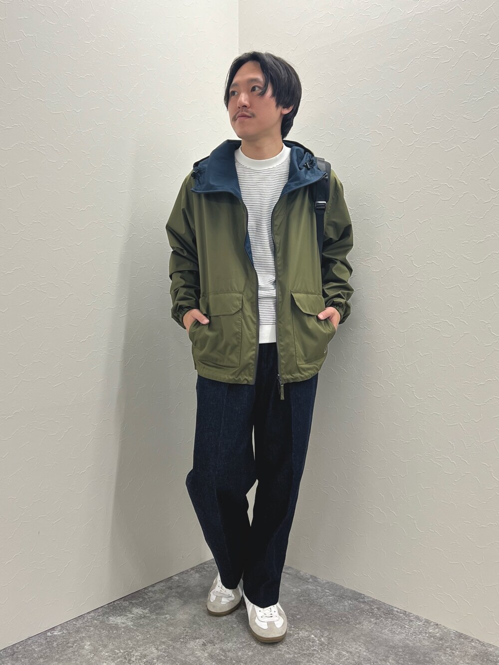 グリーン系のブルゾン、ホワイト系のTシャツ/カットソー、ブルー系のデニムパンツを着用したメンズの冬コーディネートの2枚目の写真