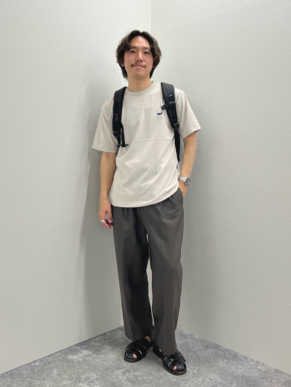 ベージュ系のTシャツ/カットソー、ブラック系のバックパック/リュック、ブラック系のサンダルを着用したメンズの春コーディネートの2枚目の写真