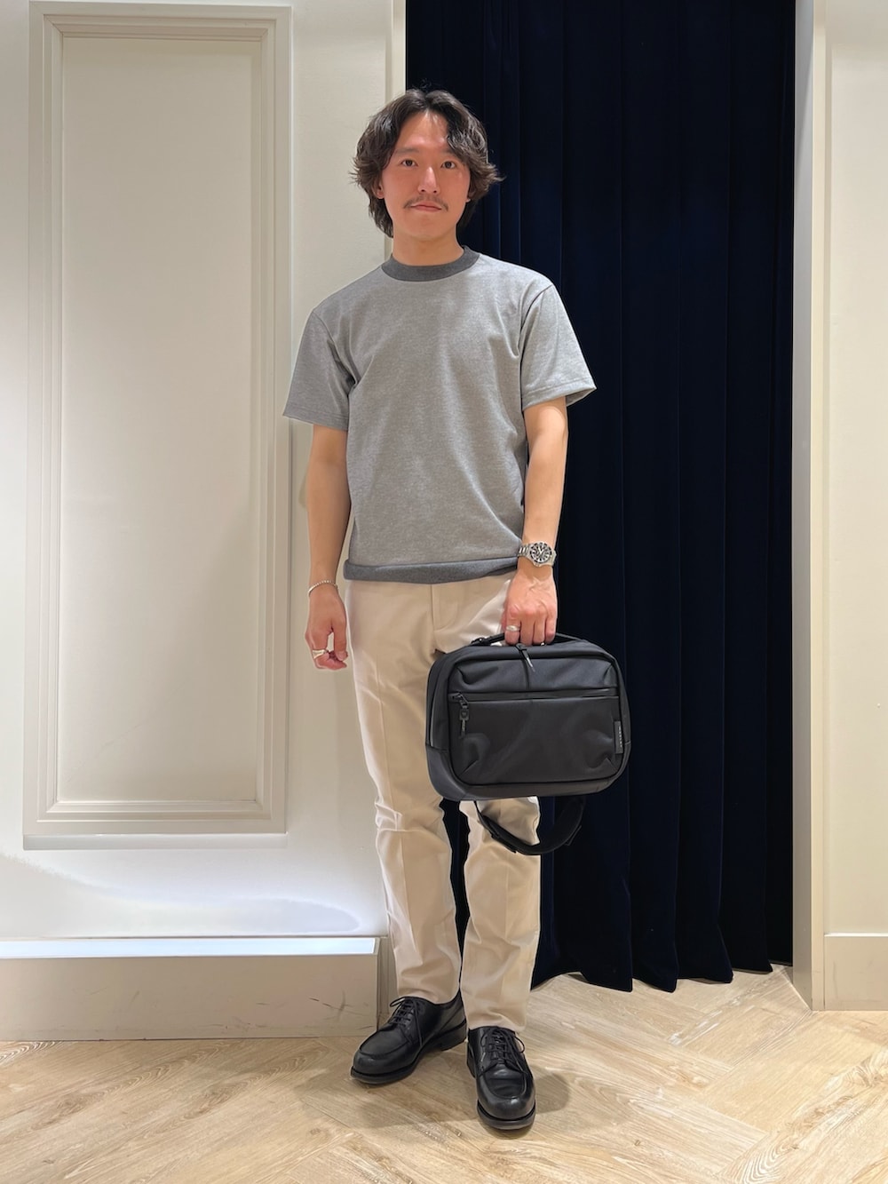 グレー系のTシャツ/カットソー、ブラック系のショルダーバッグ、ホワイト系のチノパンツを着用したメンズの春コーディネートの3枚目の写真