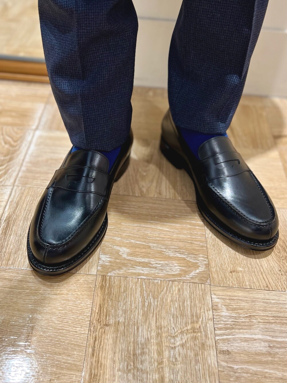 ブルー系のスラックス、ブラック系のローファー、ブルー系のネクタイを着用したメンズの冬コーディネートの8枚目の写真